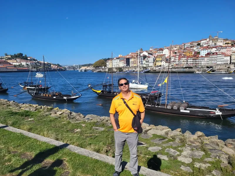 Miguel standing beside the Douro River with Porto, Portugal, rising behind him
