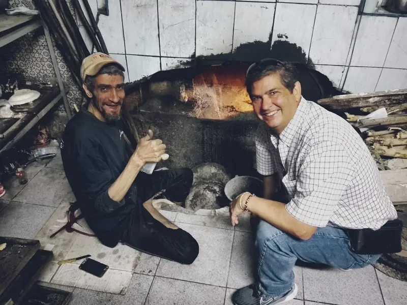 Miguel learning beside a traditional oven with a local baker