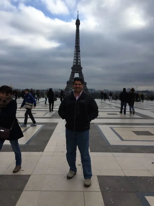 Miguel standing beneath the Eiffel Tower in Paris