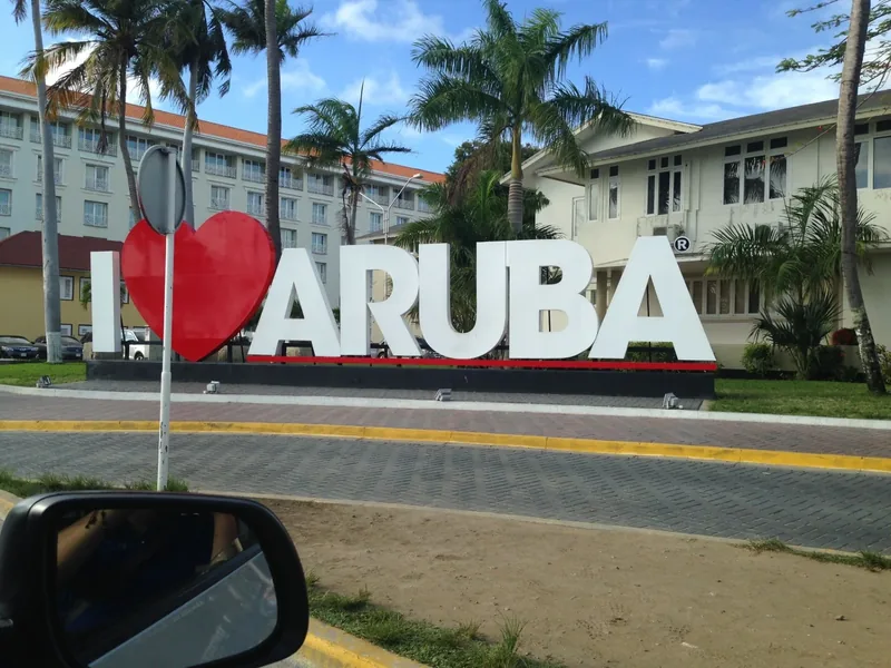 I love Aruba sign beside a palm-lined road in Aruba
