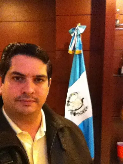Miguel posing beside a Guatemalan flag