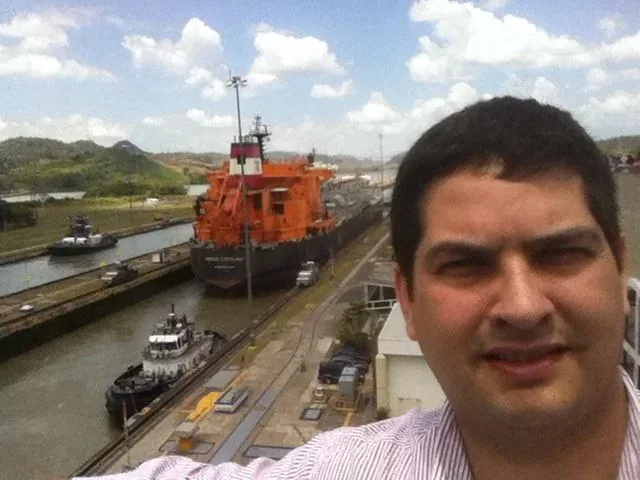 Miguel posing beside a ship moving through the Panama Canal