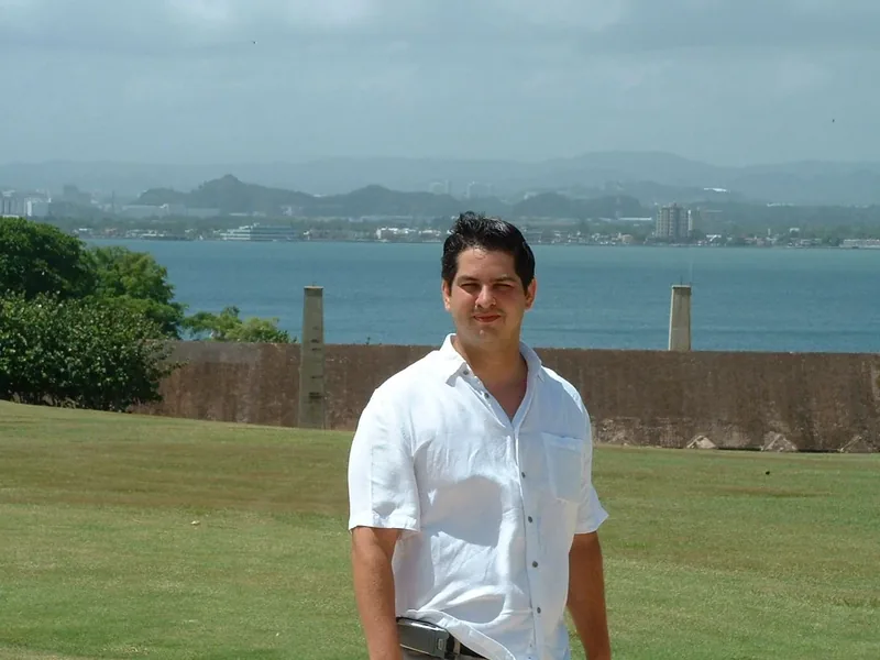 Miguel standing beside a lake with a distant shoreline behind him